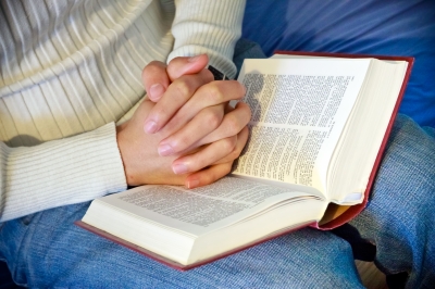 Hands folded on bible